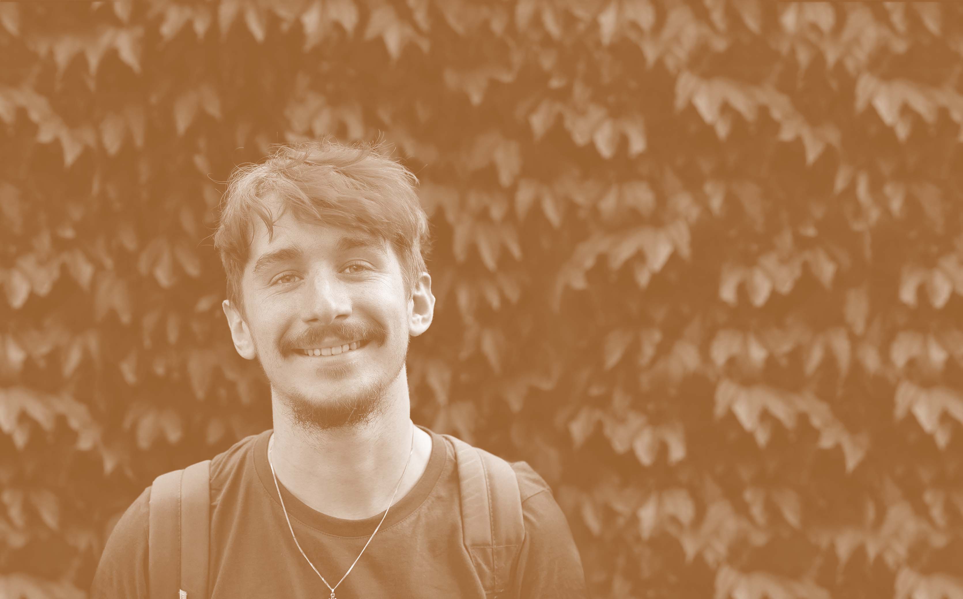 An orange-tinted picture of me smiling against a backdrop of leaves